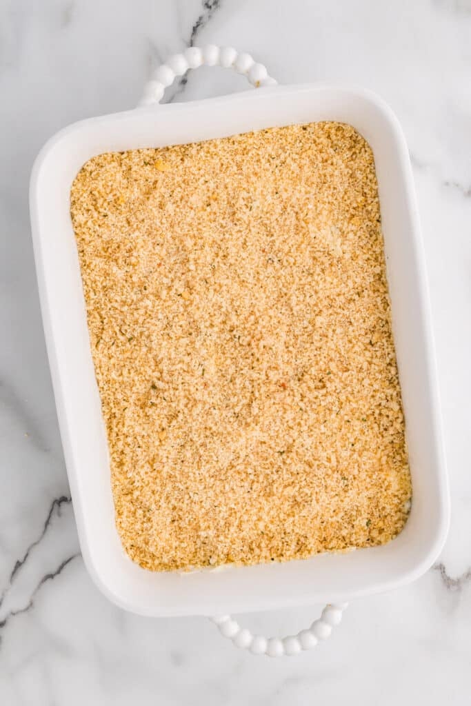 Unbaked jalapeño popper dip topped with breadcrumbs in a white baking dish.