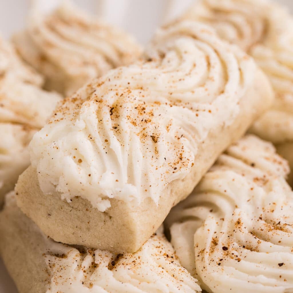 Rectangular cookies topped with piped white frosting and sprinkled with nutmeg.