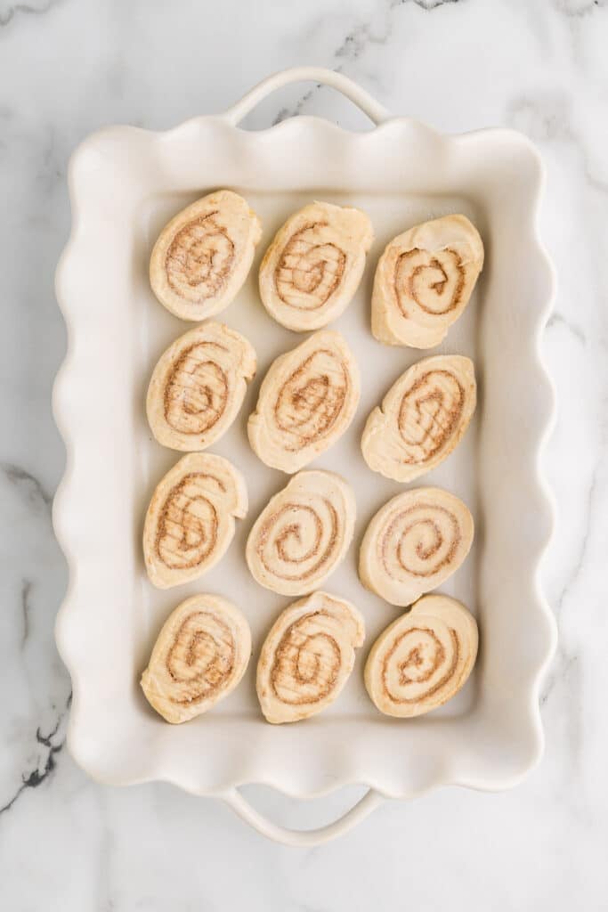 Unbaked sliced cinnamon rolls arranged in a baking dish.