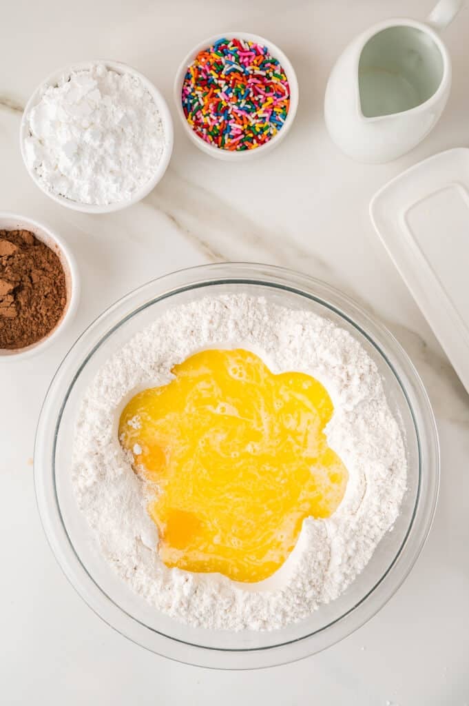 Melted butter poured over flour in a glass mixing bowl.